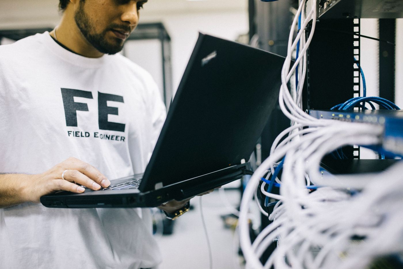 Field engineer working on a laptop beside a network rack